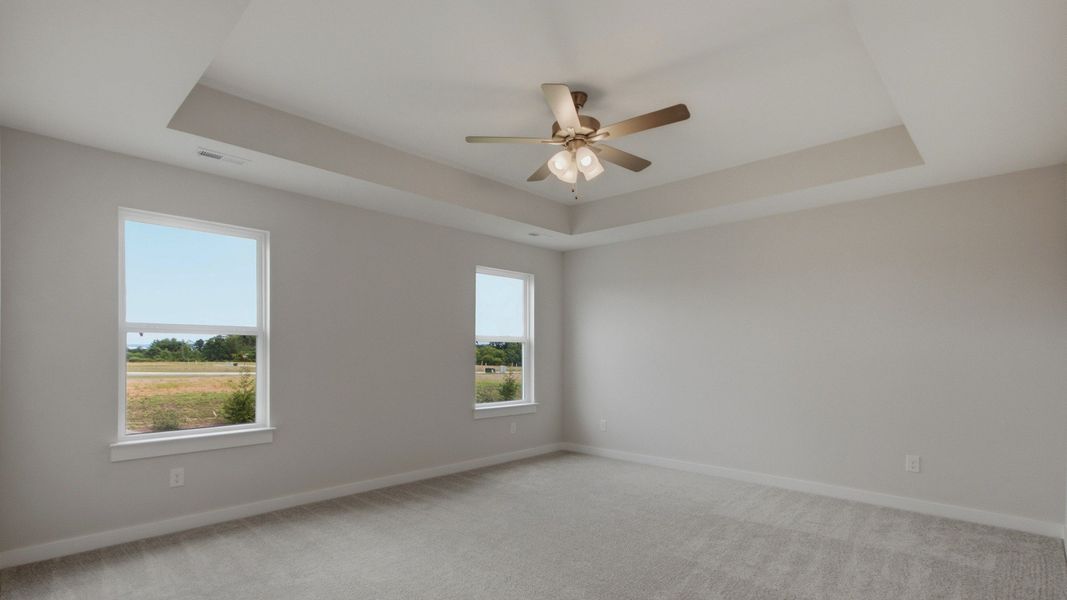 Elevated primary bedroom with tray ceilings and fan Elevated primary bedroom with tray ceilings and fan
