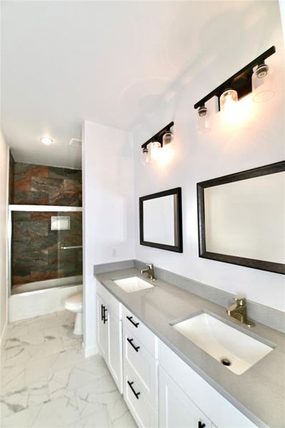 Full bathroom featuring toilet, combined bath / shower with glass door, tile patterned flooring, and vanity