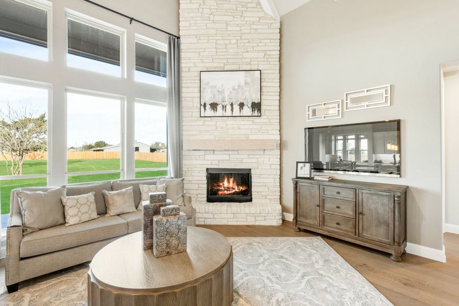 Living room with vaulted ceiling, floor-to-ceiling white stone fireplace, large windows, and hardwood floors Living room with vaulted ceiling, floor-to-ceiling white stone fireplace, large windows, and hardwood floors
