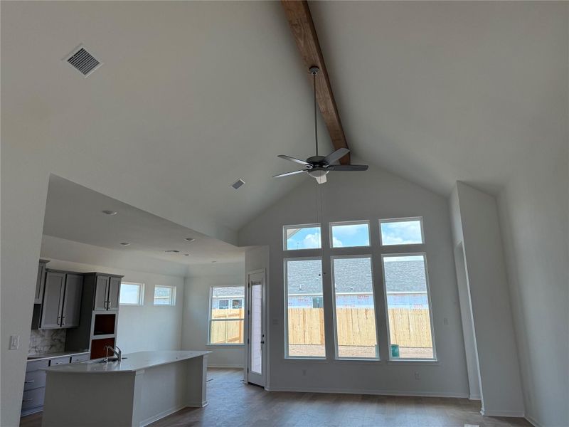 Unfurnished living room with beam ceiling, dark wood-type flooring, ceiling fan, and high vaulted ceiling Unfurnished living room with beam ceiling, dark wood-type flooring, ceiling fan, and high vaulted ceiling