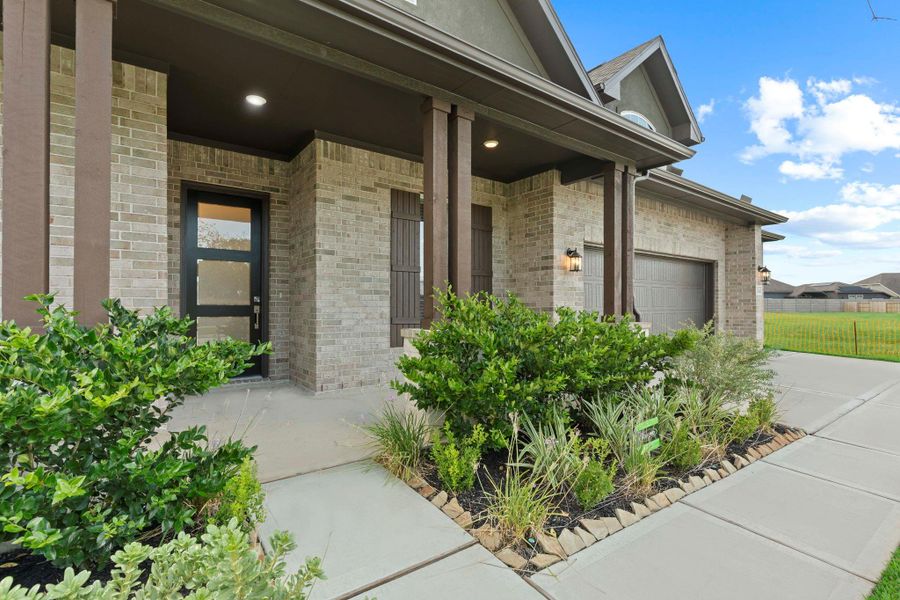 Covered front porch with elegant brick detailing, accented by fresh landscaping and a cozy spot to welcome guests or enjoy a quiet evening outdoors.  Enjoy that morning coffee watching the neighbors and children starting their day!