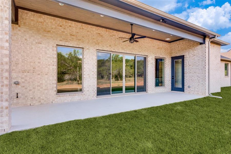 Back of property with ceiling fan, a patio, brick siding, and a yard Back of property with ceiling fan, a patio, brick siding, and a yard