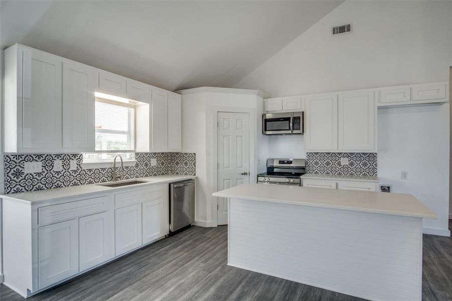 Kitchen with appliances with stainless steel finishes, sink, backsplash, and white cabinets Kitchen with appliances with stainless steel finishes, sink, backsplash, and white cabinets