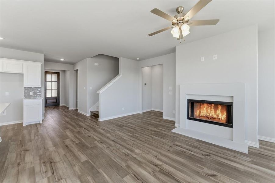 Unfurnished living room with a warm lit fireplace, ceiling fan, light wood-style floors, and recessed lighting