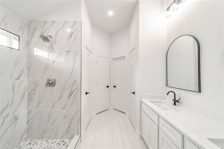 Bathroom with double vanity, a marble finish shower, a sink, and recessed lighting