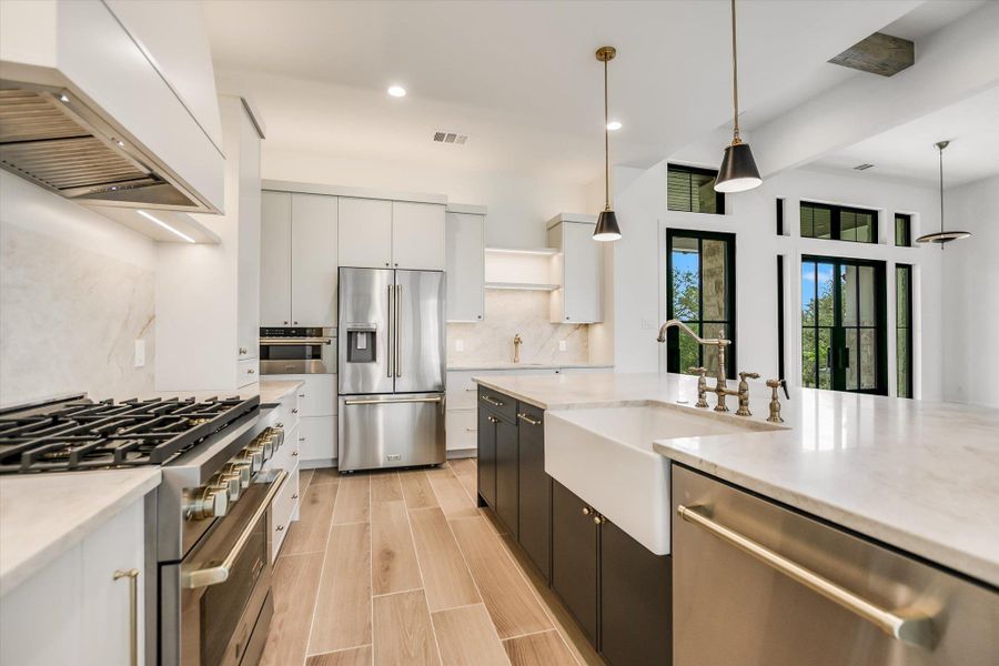 Modern kitchen featuring wood-finish flooring, light-toned countertops, and stainless steel appliances