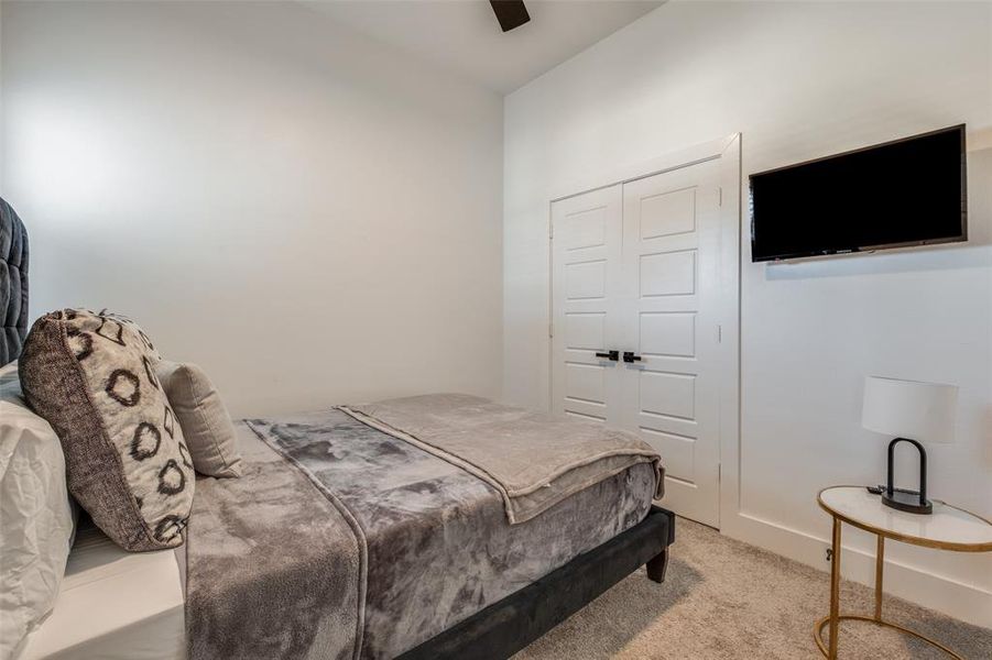 Bedroom with ceiling fan, a closet, and light carpet