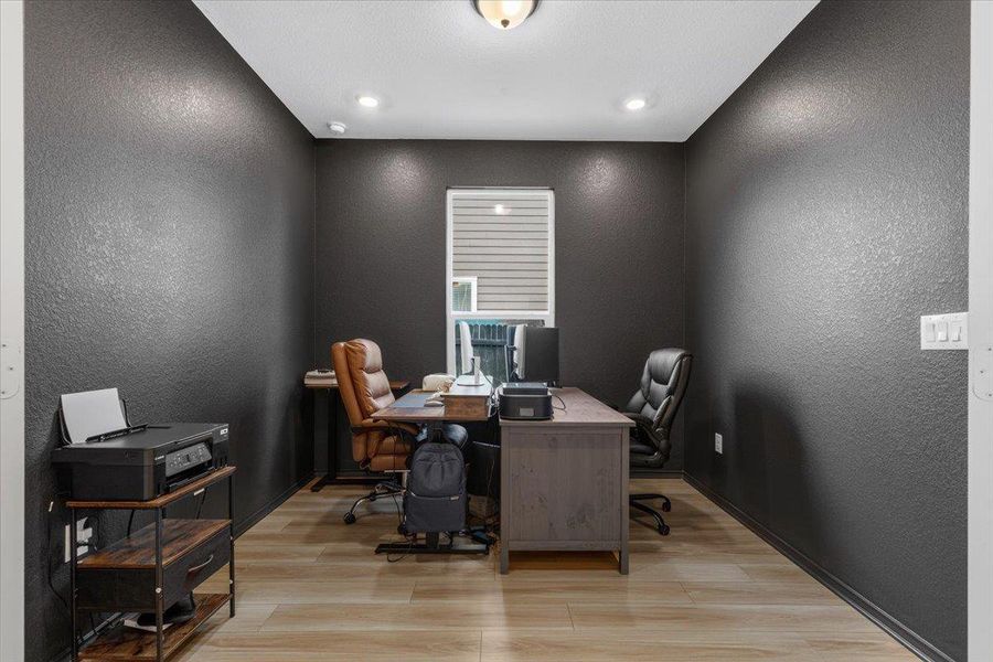 A dedicated home office provides a private and productive workspace with modern lighting and durable flooring.