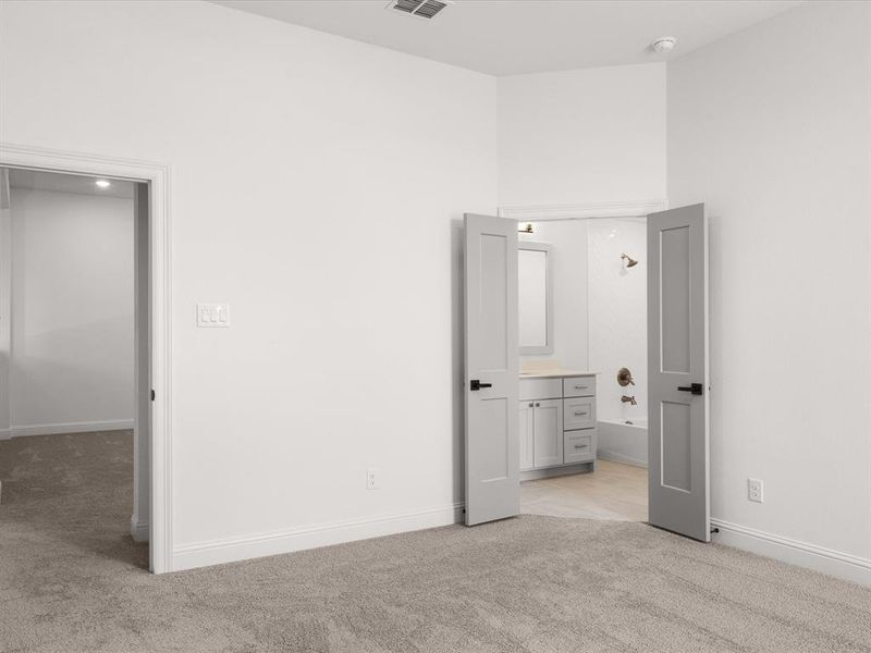 Unfurnished bedroom with light colored carpet and ensuite bathroom