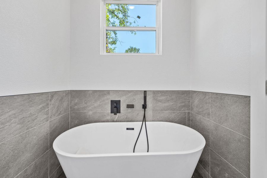 A freestanding soaking tub with contemporary fixtures anchors this private bathing space. A freestanding soaking tub with contemporary fixtures anchors this private bathing space.