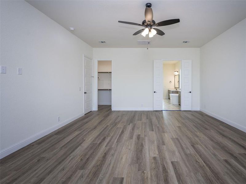 Unfurnished bedroom featuring dark wood-type flooring, a spacious closet, ensuite bath, ceiling fan, and a closet Unfurnished bedroom featuring dark wood-type flooring, a spacious closet, ensuite bath, ceiling fan, and a closet