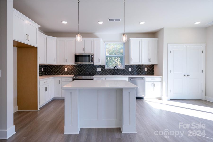 Kitchen with upgraded cabinets, Stainless appliances and lighting package. Kitchen also features a trimmed island and glossy herringbone patterned backsplash