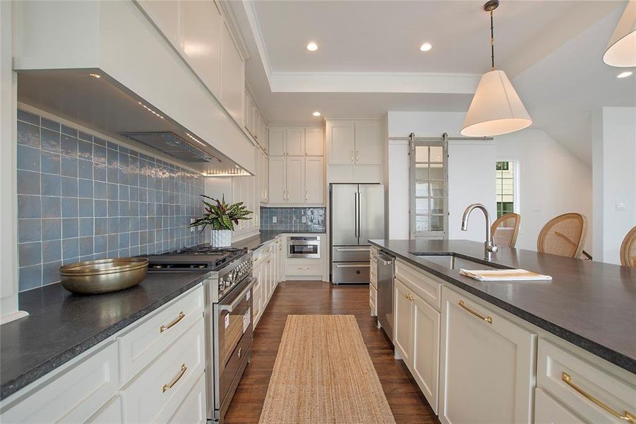 Kitchen featuring tasteful backsplash, sink, pendant lighting, dark hardwood / wood-style floors, and premium appliances