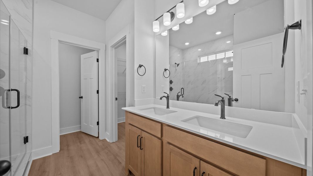 Highly functional and elegant en-suite with dual vanities, tiled walk-in shower, and refined finishes