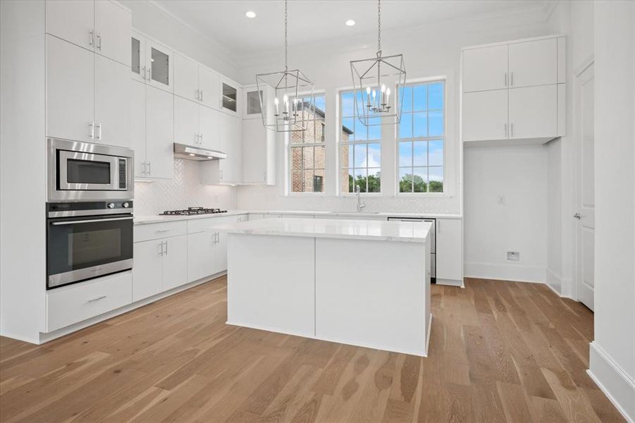 Kitchen with white cabinets, appliances with stainless steel finishes, a center island, and recessed lighting Kitchen with white cabinets, appliances with stainless steel finishes, a center island, and recessed lighting