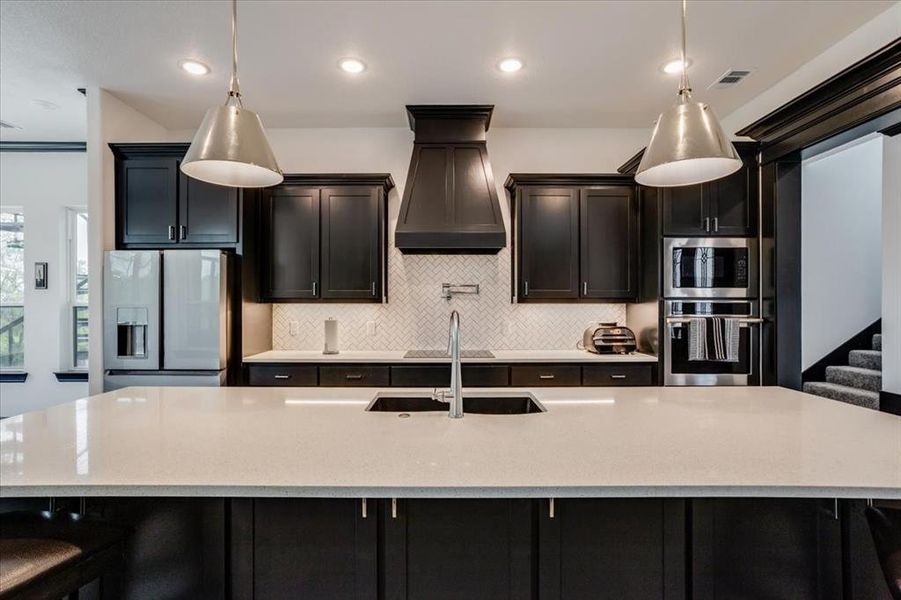 Kitchen featuring stainless steel appliances, light stone countertops, a breakfast bar area, a spacious island, and backsplash