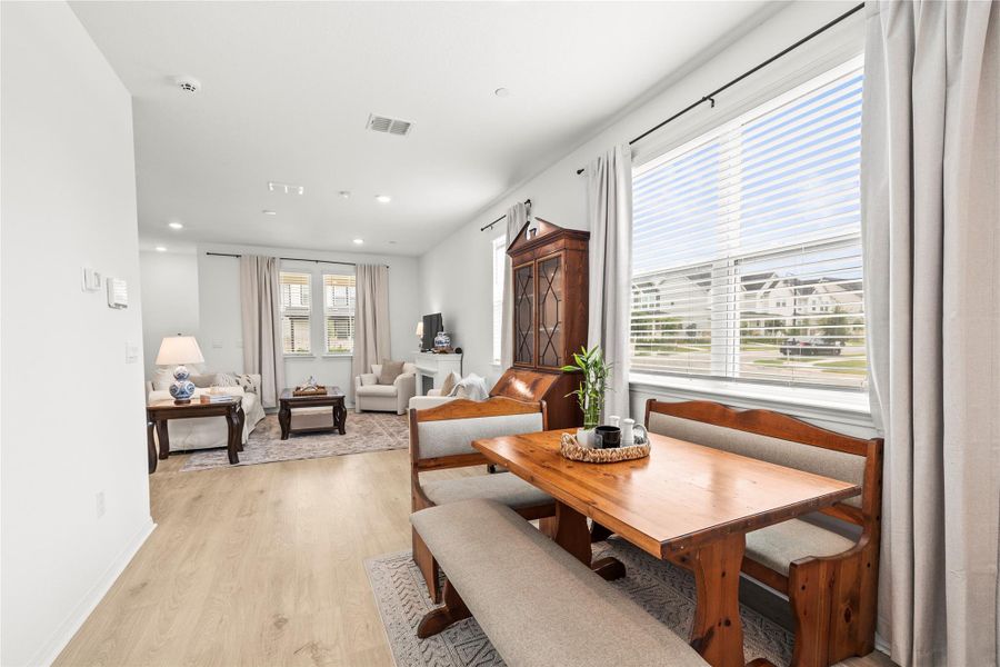 Natural light streams into this combined dining and living area, highlighting the warm wood flooring.