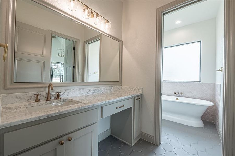 Bathroom featuring a freestanding tub, dark tile patterned floors, and vanity Bathroom featuring a freestanding tub, dark tile patterned floors, and vanity