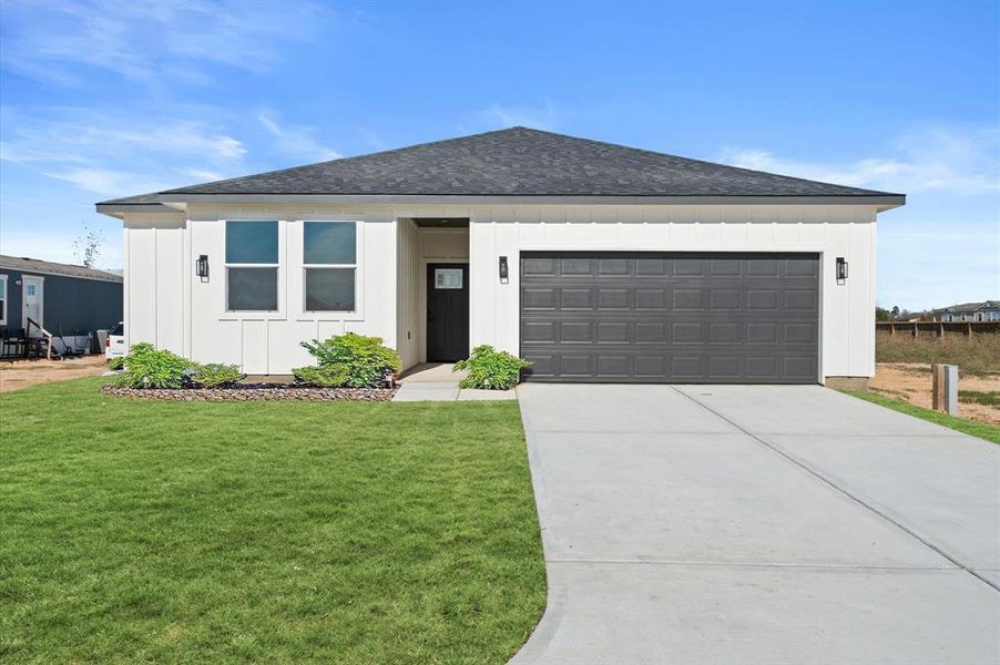 This is a modern single-story home featuring a clean design with a two-car garage, a neat front lawn, and minimalistic landscaping.