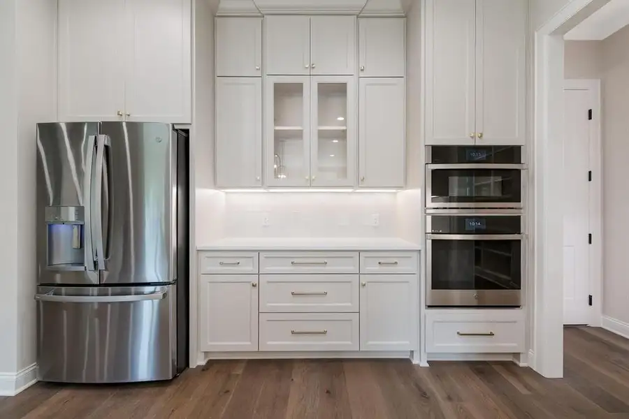 Kitchen featuring stainless steel appliances, white cabinetry, and dark wood-style floors Kitchen featuring stainless steel appliances, white cabinetry, and dark wood-style floors