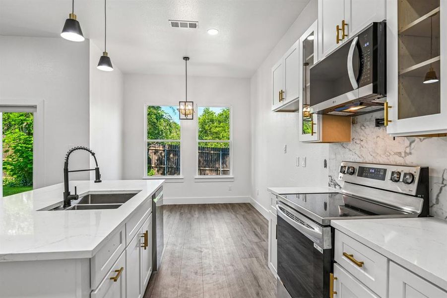 Kitchen featuring white cabinetry, a large center island with an undermount sink, white countertops, and a full suite of stainless steel appliances