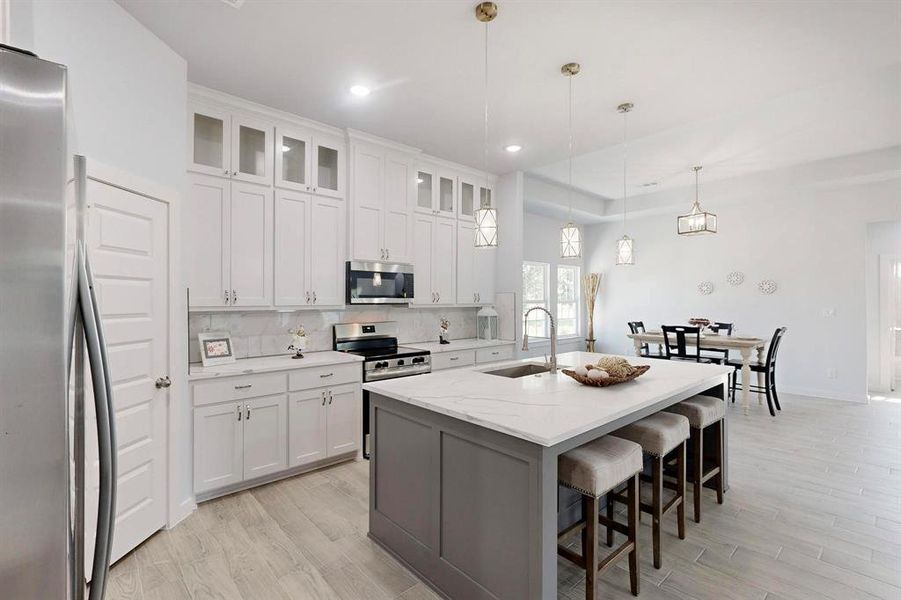 Kitchen featuring tasteful backsplash, stainless steel appliances, glass insert cabinets, hanging light fixtures, and white cabinets Kitchen featuring tasteful backsplash, stainless steel appliances, glass insert cabinets, hanging light fixtures, and white cabinets