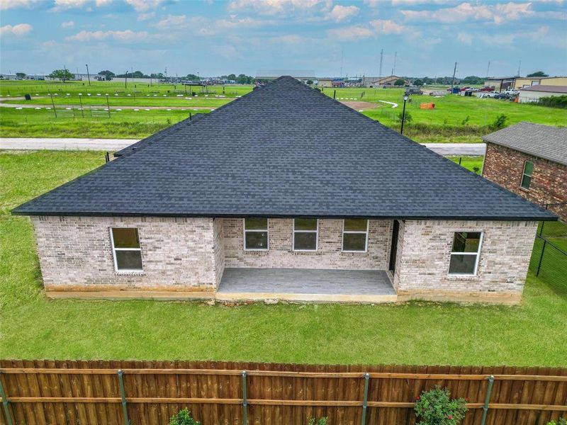 Back of house featuring a shingled roof, a patio area, and brick siding
