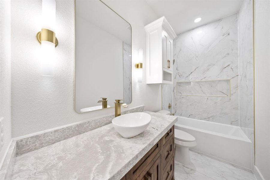 Bathroom featuring vanity, light marble finish flooring, bathing tub / shower combination, and a textured wall