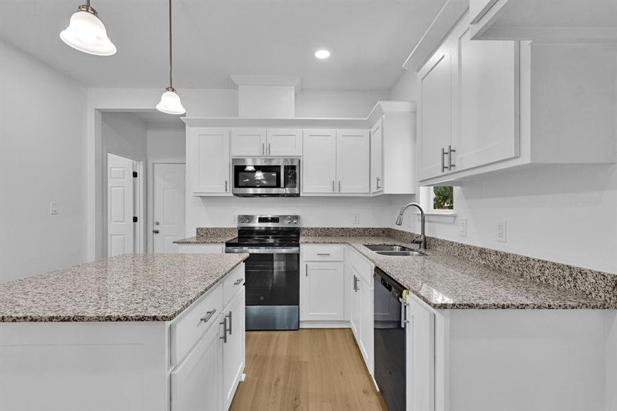 Kitchen with stainless steel appliances, light stone counters, white cabinetry, pendant lighting, and light wood finished floors Kitchen with stainless steel appliances, light stone counters, white cabinetry, pendant lighting, and light wood finished floors