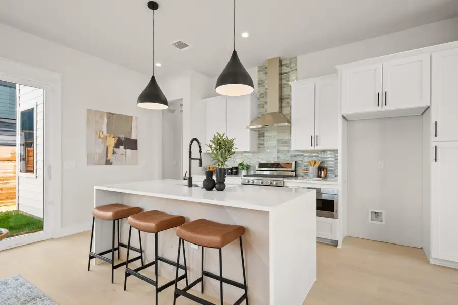 Kitchen featuring decorative backsplash, pendant lighting, white cabinets, wall chimney exhaust hood, and light stone countertops