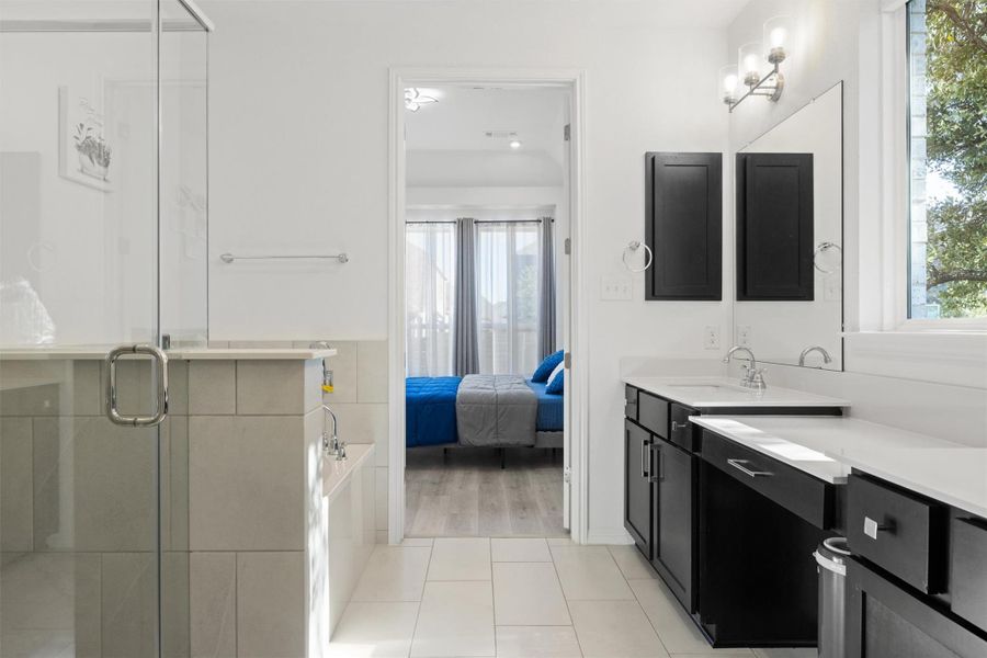 Bathroom featuring light tile patterned flooring, connected bathroom, vanity, a stall shower, and a bath Bathroom featuring light tile patterned flooring, connected bathroom, vanity, a stall shower, and a bath