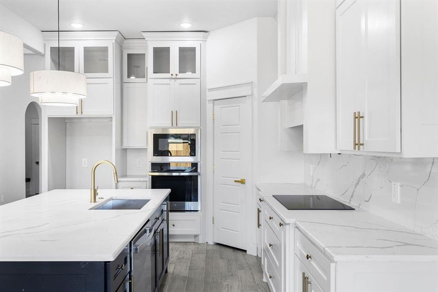 Kitchen featuring light stone counters, stainless steel appliances, sink, pendant lighting, and white cabinets