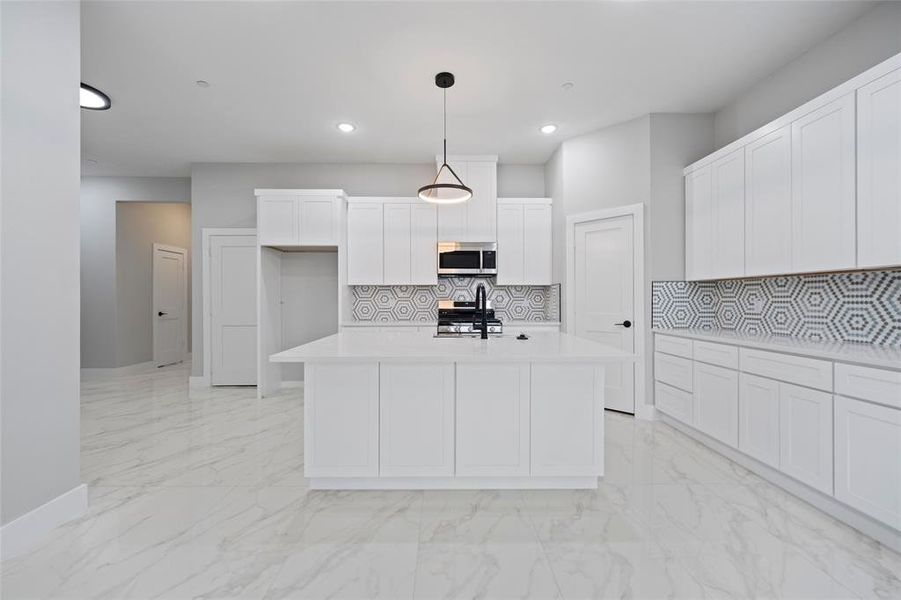 Kitchen featuring decorative backsplash, light countertops, hanging light fixtures, appliances with stainless steel finishes, and marble finish floor