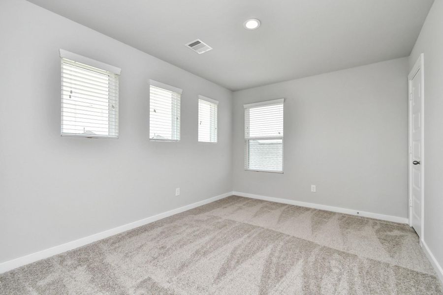 Secondary bedroom. Plush carpet, neutral paint color, large windows, and spacious closets. Sample photo of completed home with similar floor plan. Actual colors and selections may vary.