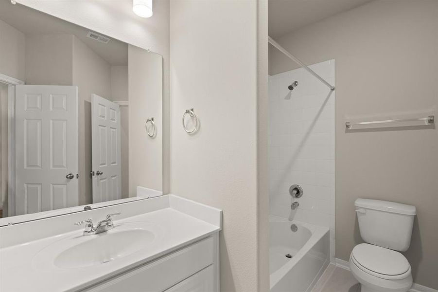 The secondary bath features tile flooring, white cabinetry and light countertops and a shower/tub combo. Perfect for accommodating any visiting family and friends.