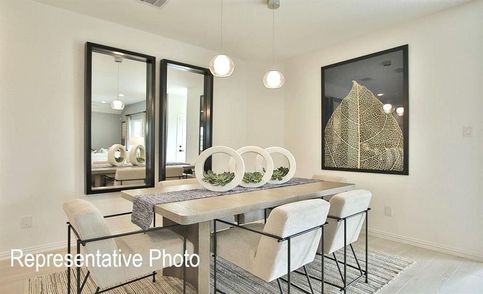 Dining area featuring light-toned wood-finish flooring, white walls, and two contemporary pendant light fixtures