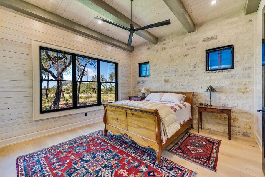 Bedroom with light wood finished floors, a wooden ceiling with exposed beams, and a ceiling fan