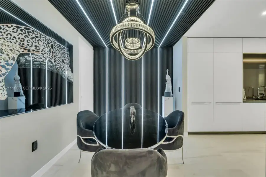 Black slatted wall paneling with integrated vertical LED lighting, three-tier crystal chandelier, high-gloss white cabinetry, and light-toned large-format flooring Black slatted wall paneling with integrated vertical LED lighting, three-tier crystal chandelier, high-gloss white cabinetry, and light-toned large-format flooring