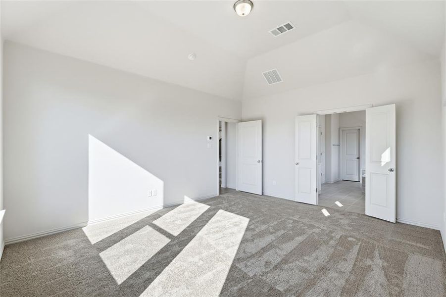 Unfurnished bedroom with carpet and high vaulted ceiling