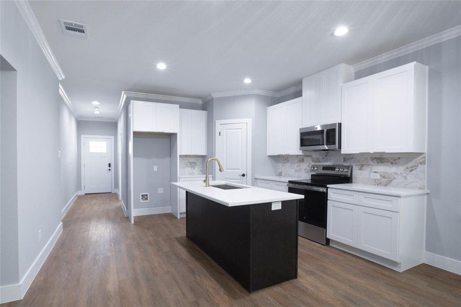 Kitchen featuring crown molding, white cabinets, stainless steel appliances, dark wood-style floors, and decorative backsplash