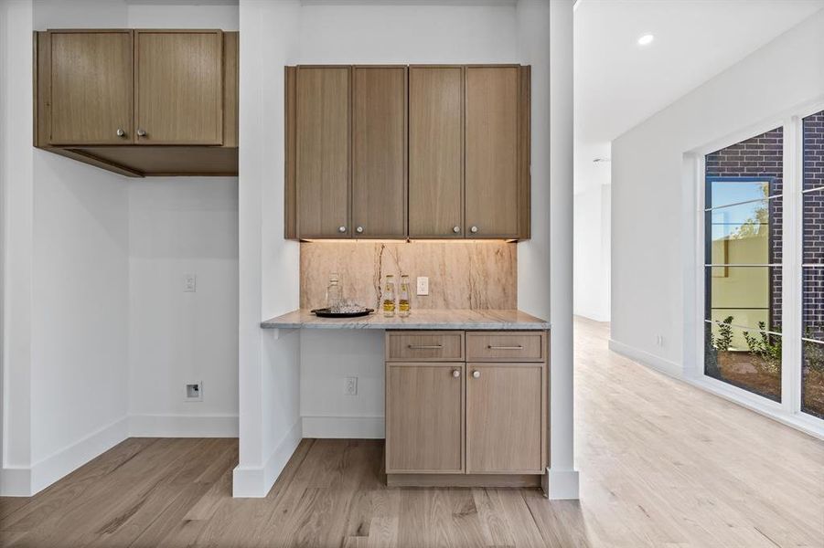 Kitchen featuring tasteful backsplash, light stone countertops, and light hardwood / wood-style flooring