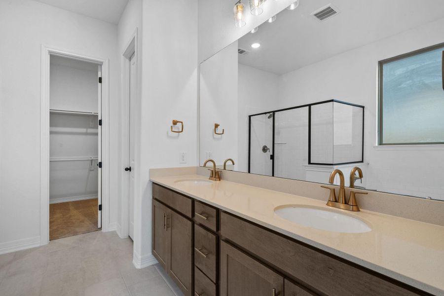 An oversized vanity outfitted with brass fixtures sets the scene for laid back glamour.
