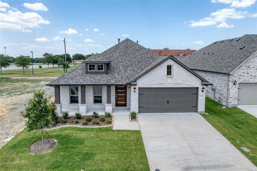 View of front of property featuring a front yard, roof with shingles, brick siding, driveway, and a garage View of front of property featuring a front yard, roof with shingles, brick siding, driveway, and a garage