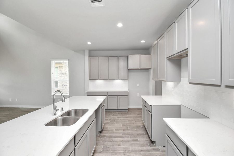 Another view of the kitchen show casing the abundance of counter top space. Sample photo of completed home with similar floor plan. Actual colors and selections may vary.