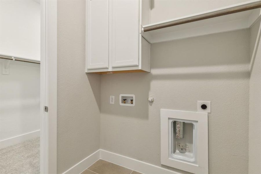 Clothes washing area with hookup for an electric dryer, cabinets, hookup for a gas dryer, washer hookup, and light tile patterned flooring