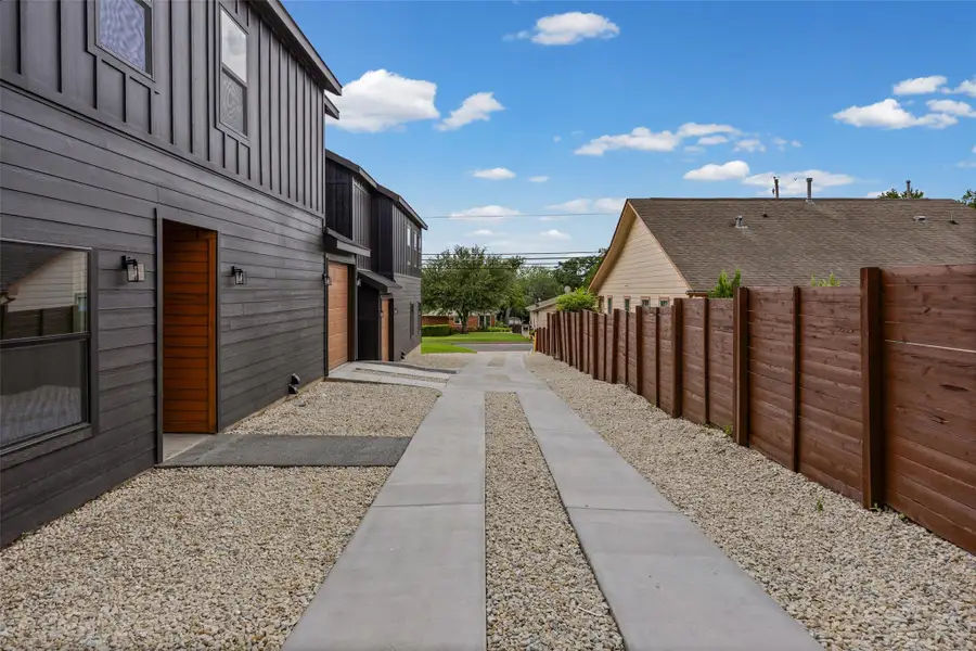 A modern townhouse exterior showcases dark siding, contrasting wood accents, and a distinctive gravel driveway leading to the front. A modern townhouse exterior showcases dark siding, contrasting wood accents, and a distinctive gravel driveway leading to the front.