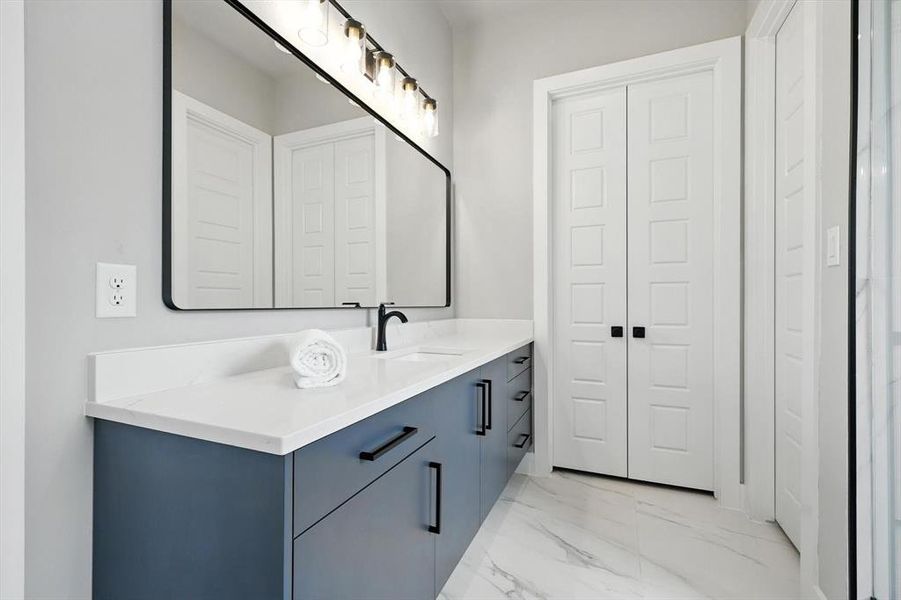 Bathroom with vanity, marble look tiles, and a closet Bathroom with vanity, marble look tiles, and a closet