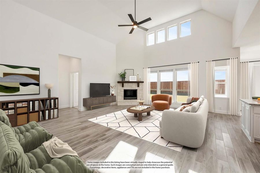 Living room with high vaulted ceiling, stone fireplace, ceiling fan, and large windows with wood-look floors Living room with high vaulted ceiling, stone fireplace, ceiling fan, and large windows with wood-look floors