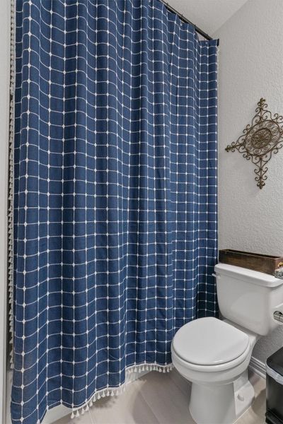 Bathroom featuring a textured wall and curtained shower