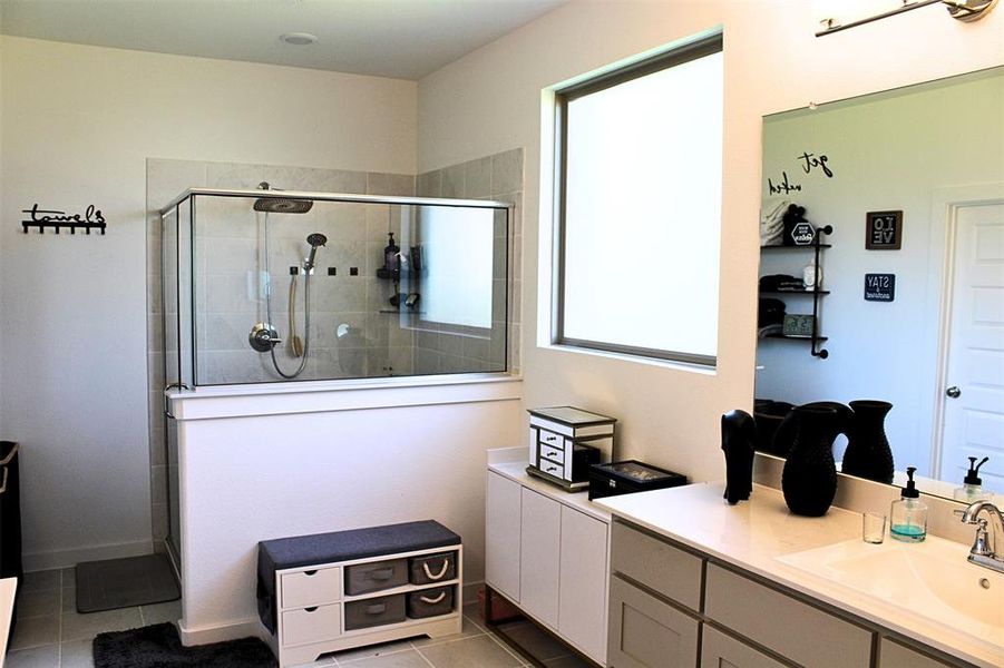 Primary bath featuring vanity, light tile patterned floors, and a tile shower